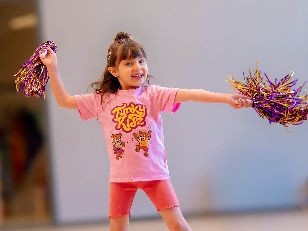 Glad flicka dansar med pompoms på FunkyKidz
