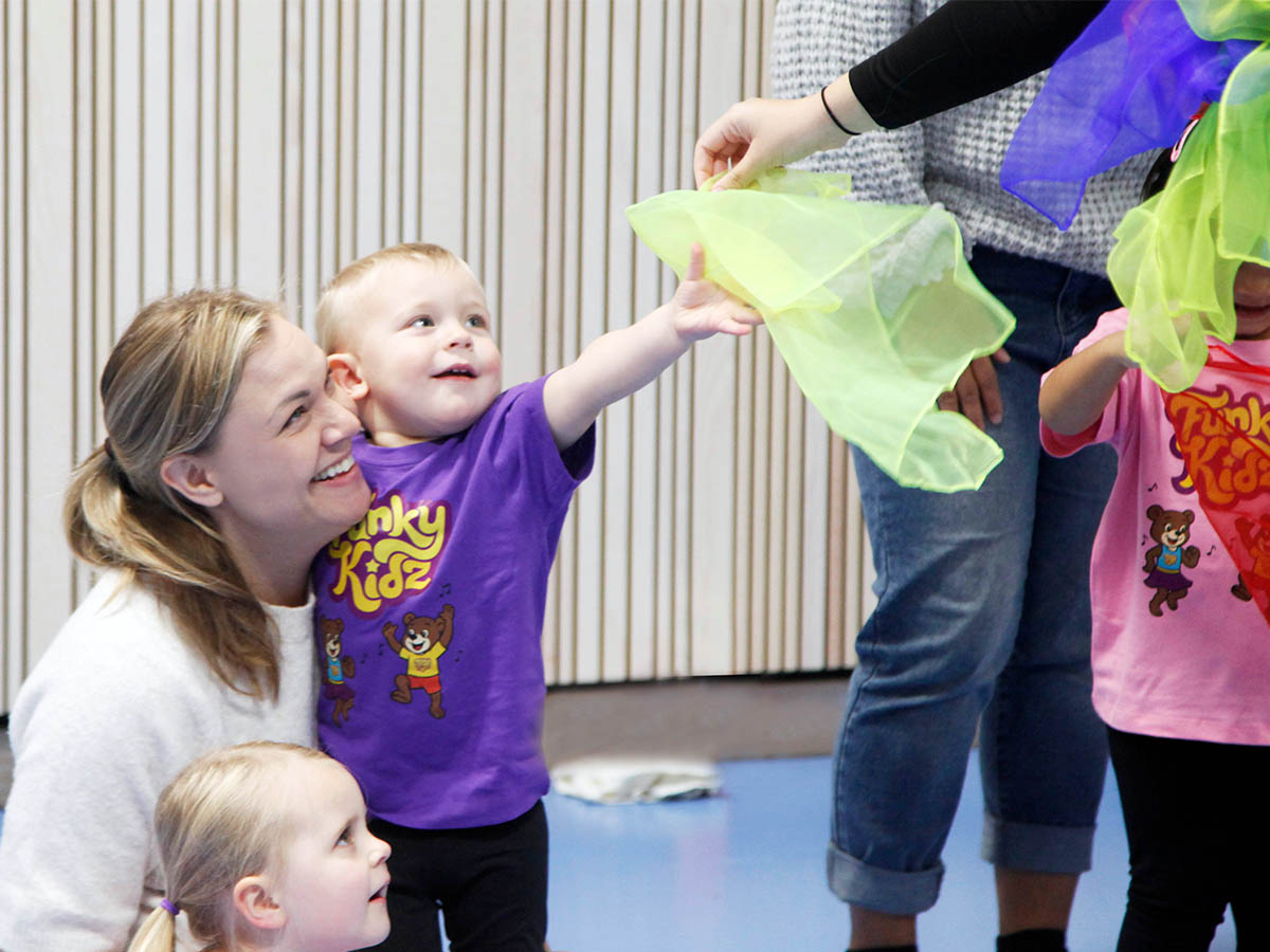 Förälder och barn leker med färgglada scarfs på FunkyKidz
