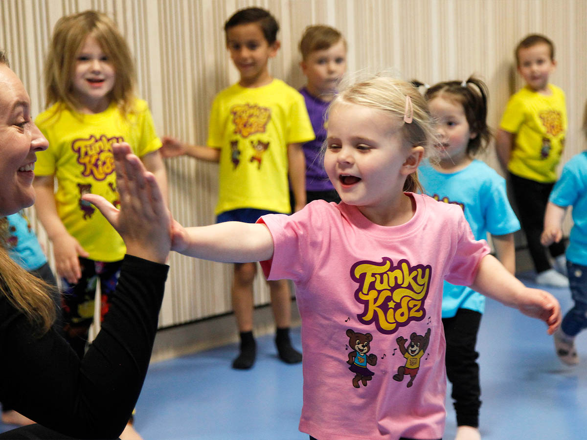 Barn ger ledare high five på FunkyKidz danskurs