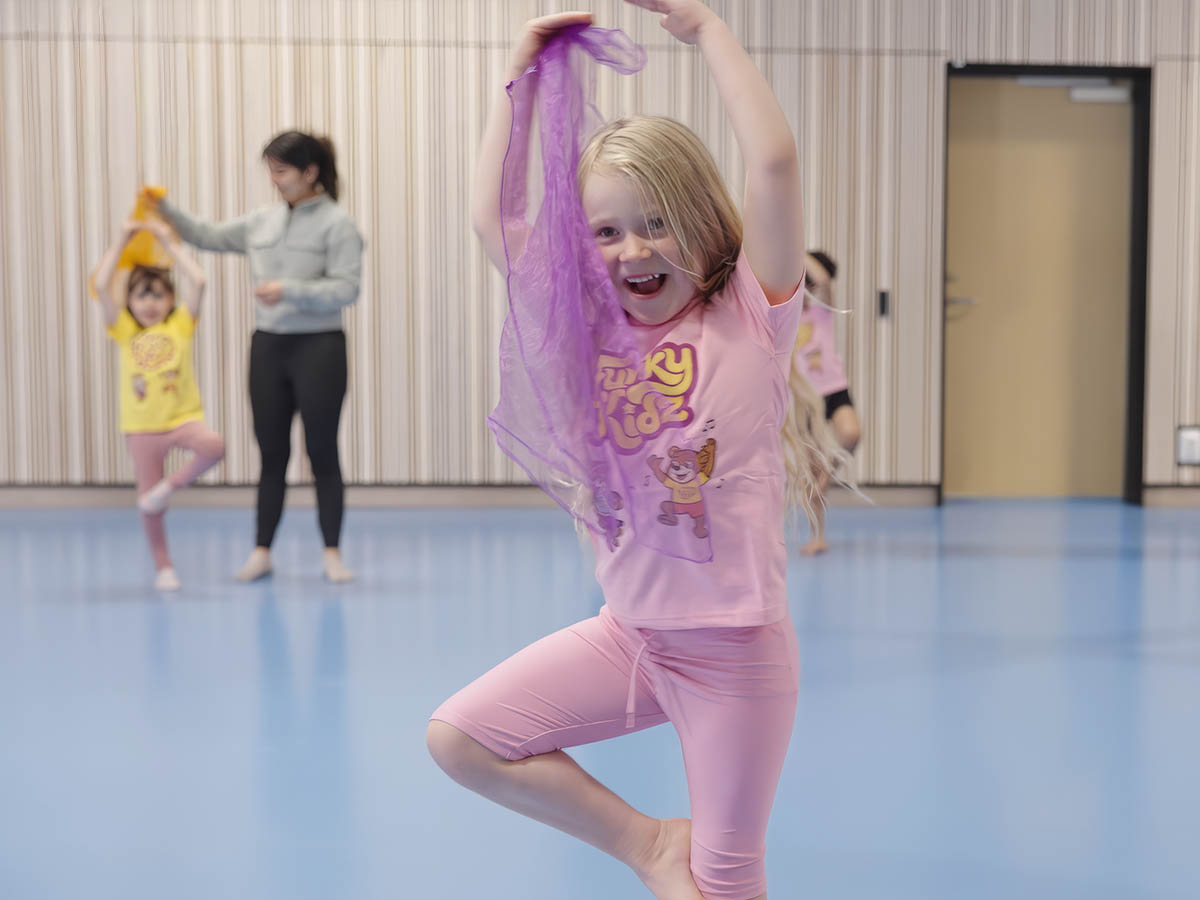 Barn dansar och viftar med ett lila tygsjal.