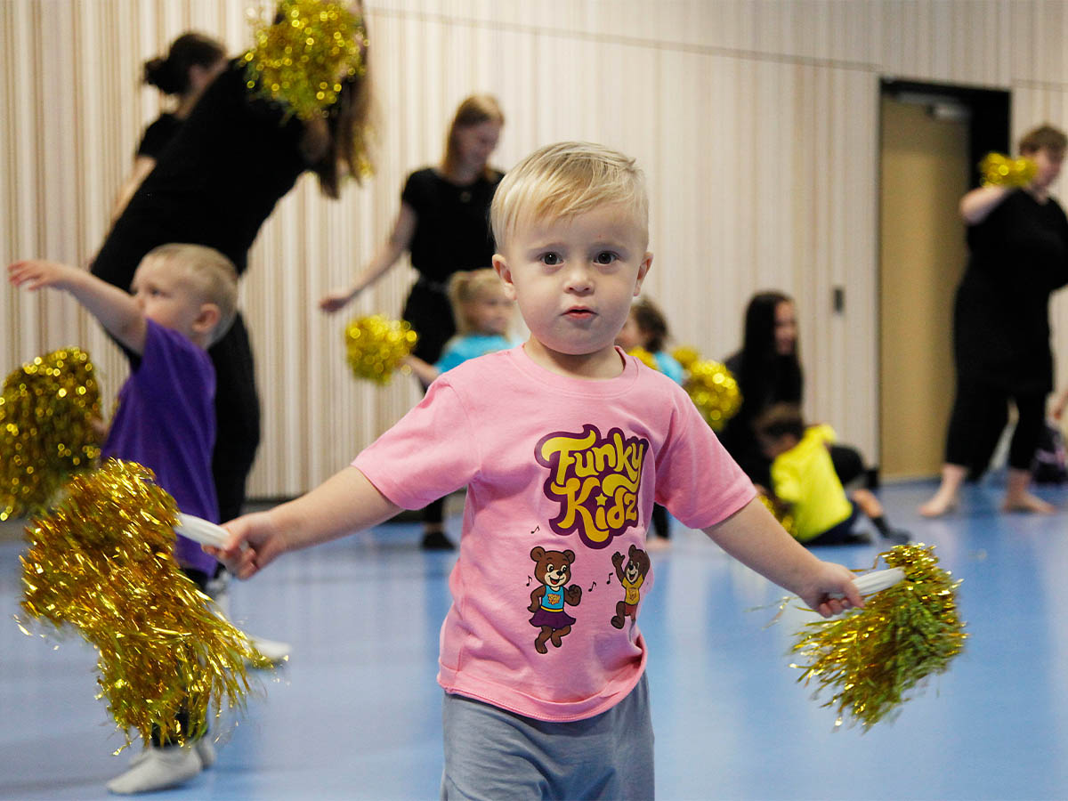 Litet barn dansar med guldpompoms på FunkyKidz